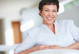 Smiling mature woman on couch Buy Stock